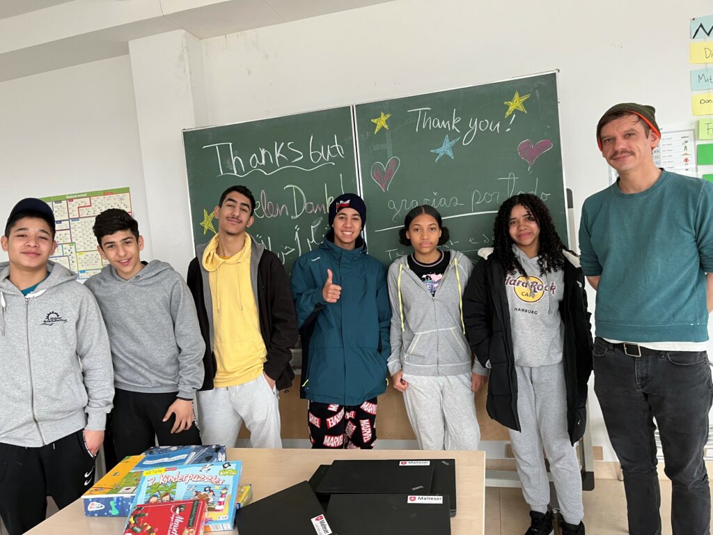 Niños y jóvenes en el centro de acogida inicial con ordenadores portátiles donados